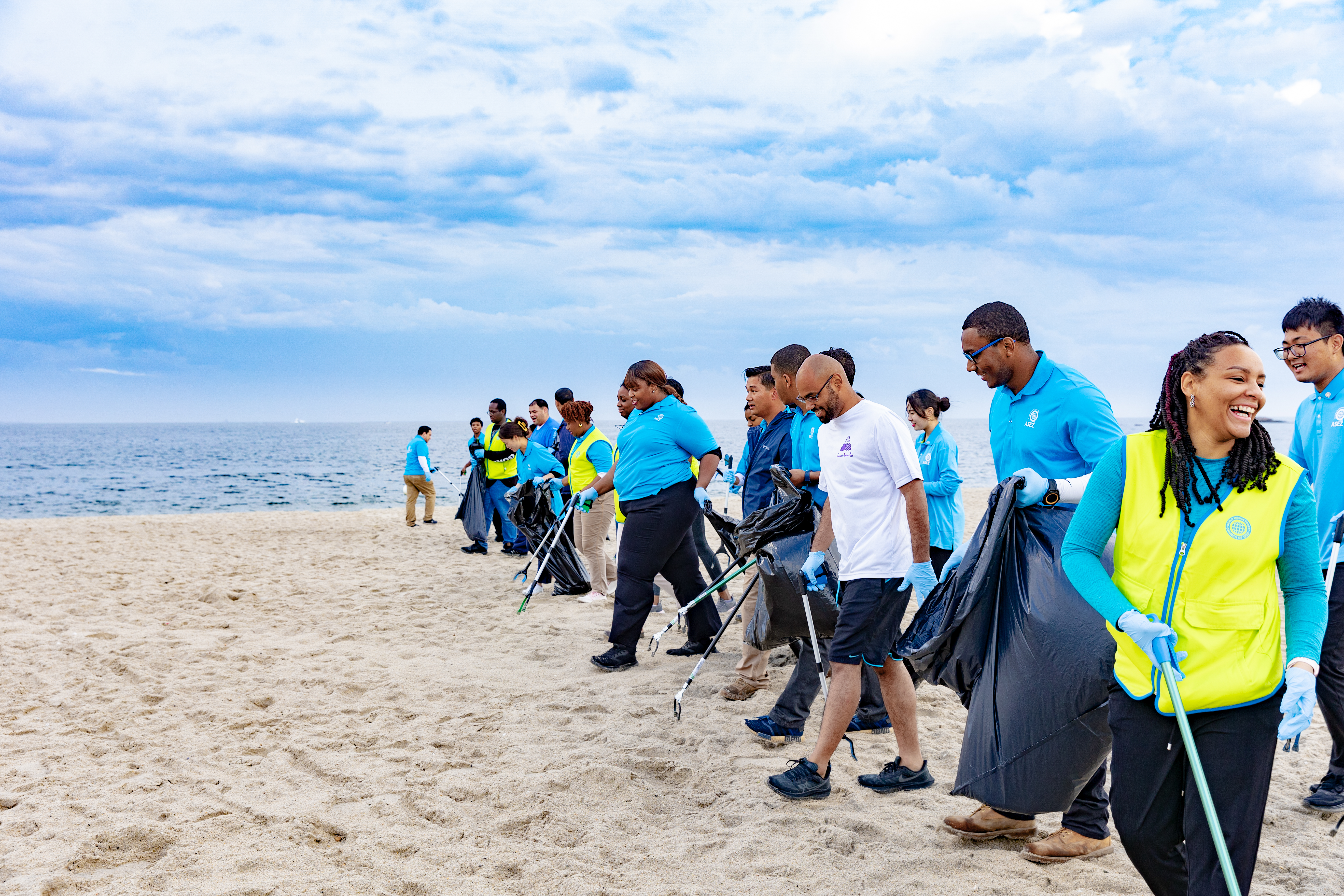 Volunteers make a line to gather trash on the beach